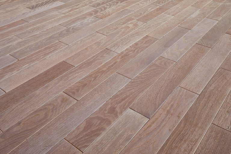 Close-up of a smooth wooden floor with light brown planks arranged in a staggered pattern.
