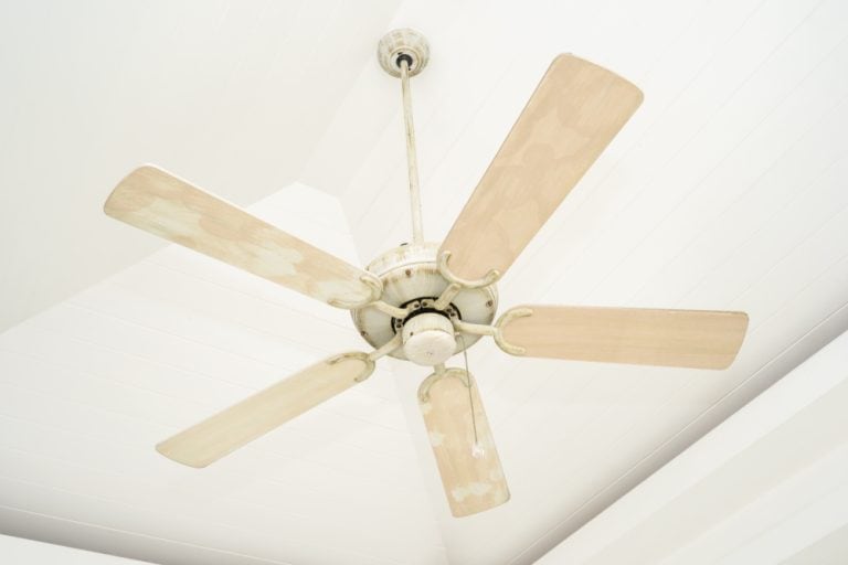 A ceiling fan with weathered paint.