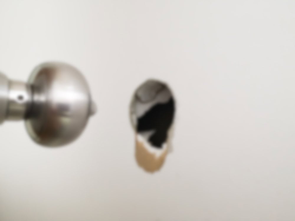 Door knob and damaged drywall with exposed hole