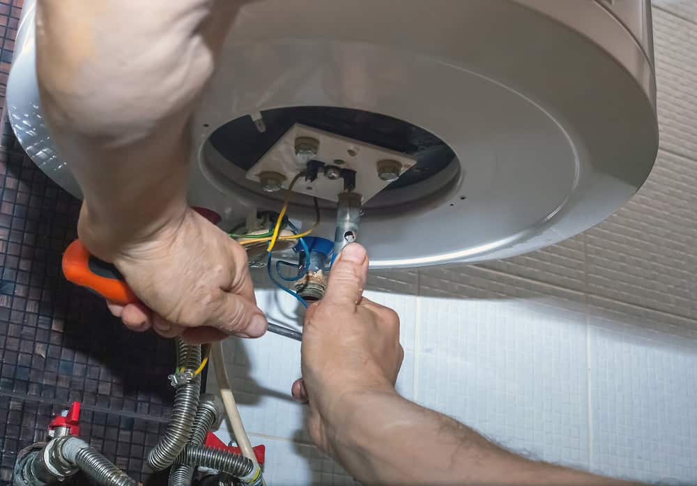 Technician repairing the internal wiring of a wall-mounted water heater.