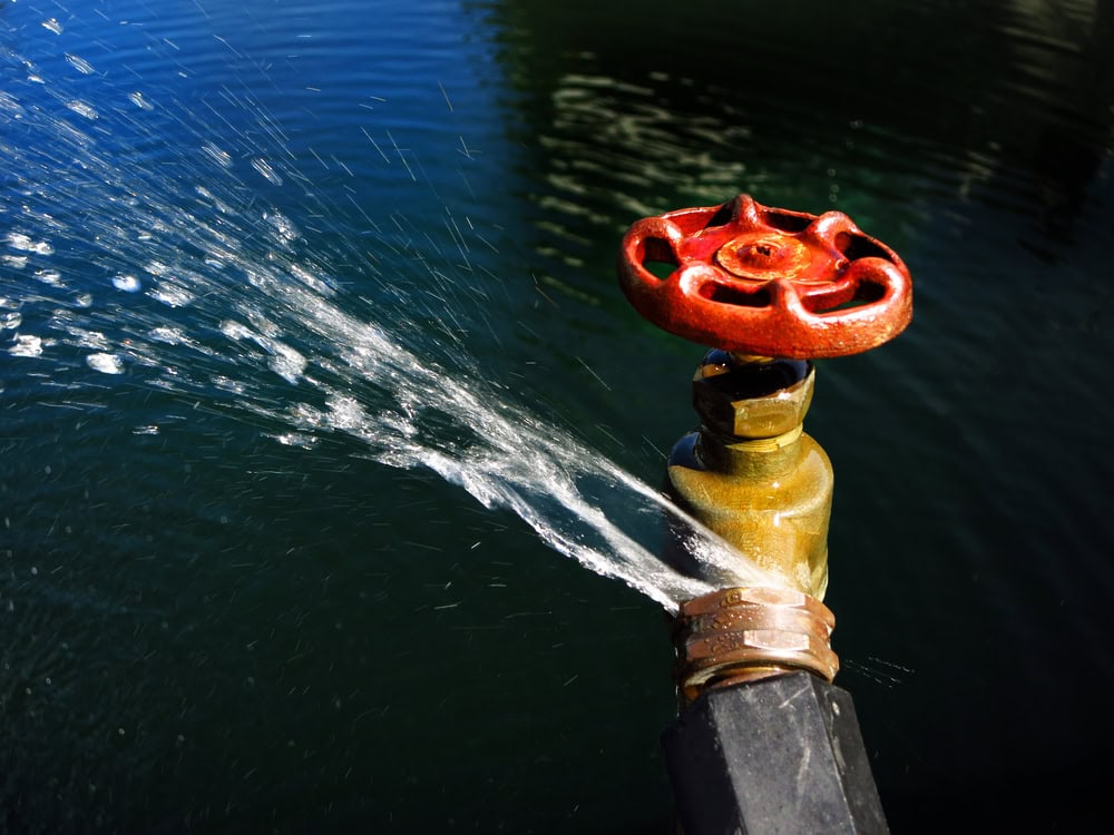 Water gushing from a leaky outdoor faucet.