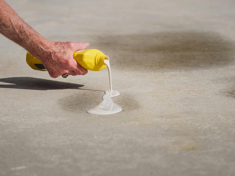 Pouring concrete crack filler to repair a damaged surface.