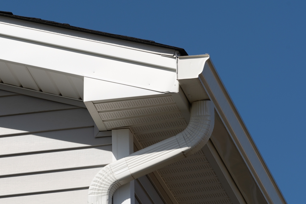 White rain gutter and soffit detail against clear blue sky, showcasing clean residential exterior trim work