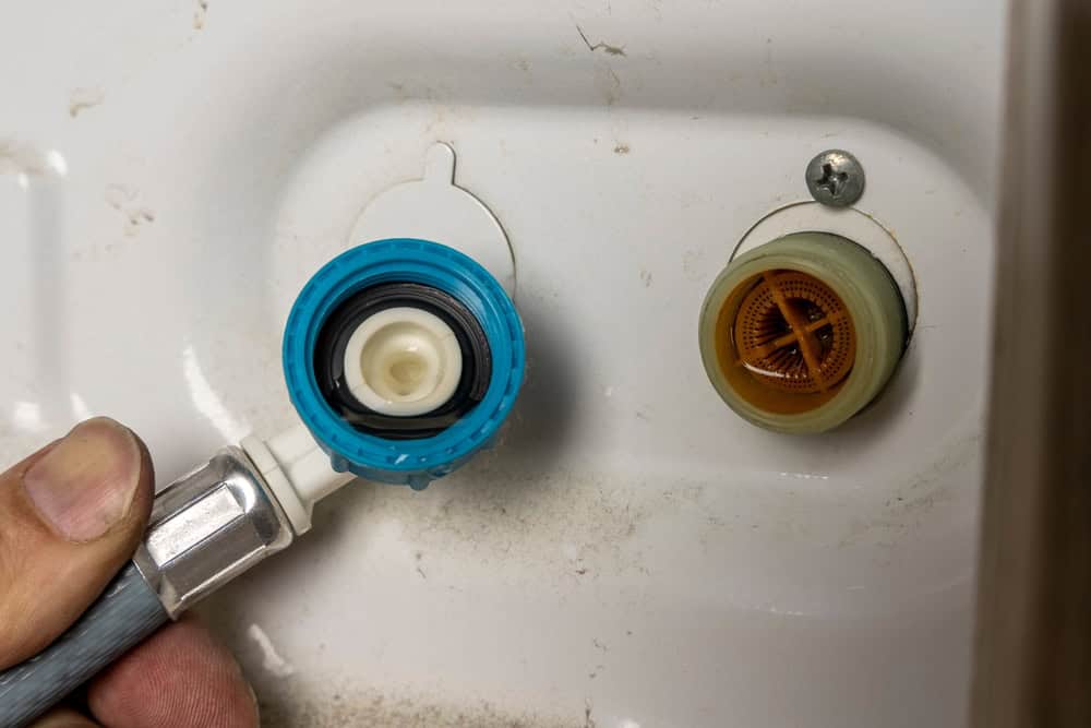 Connecting the water supply to the washing machine inlet.