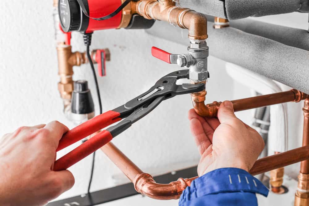 A plumber expertly adjusts a pipe fitting with precision tools.