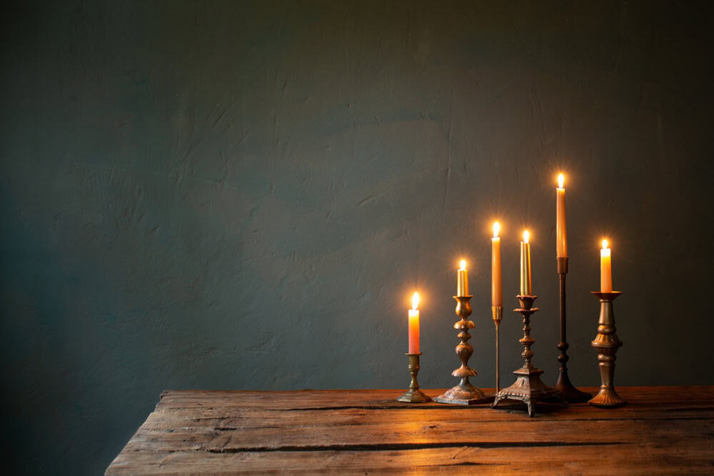 A warm glow from vintage candlesticks on a rustic wooden table.