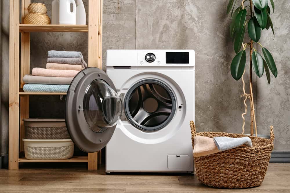 A cozy laundry corner with a modern washing machine, neatly folded towels, and a touch of greenery.