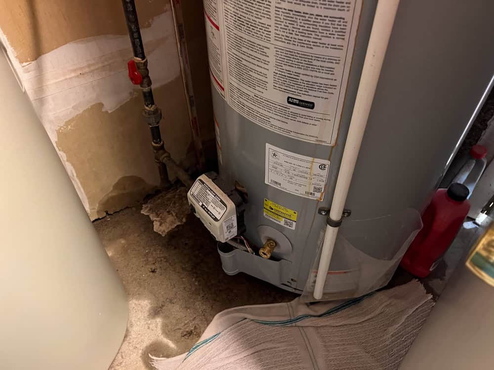 Leaking water heater with corrosion and exposed wiring.
