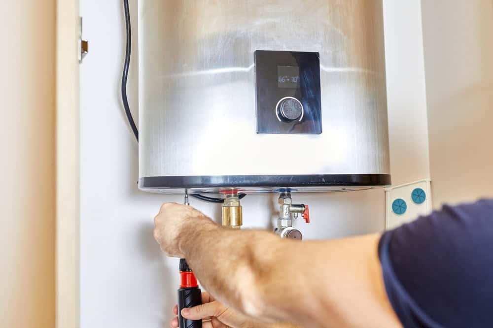 A technician adjusts the settings on a wall-mounted water heater.