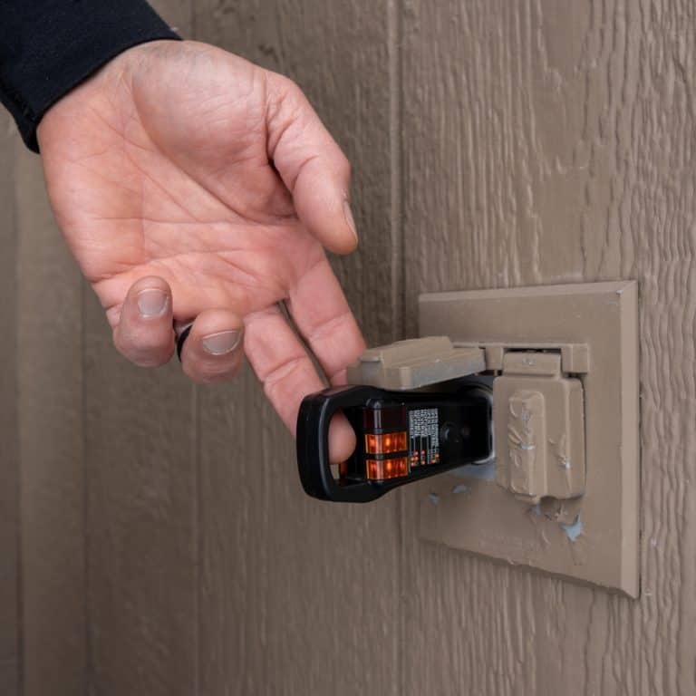 Testing an outdoor electrical outlet with a circuit analyzer to ensure safe wiring and proper grounding.