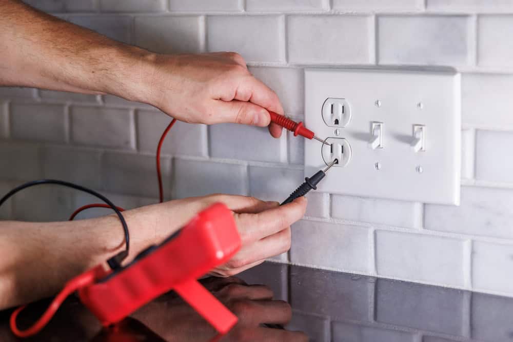 Testing the electrical outlet with a multimeter to ensure safety.
