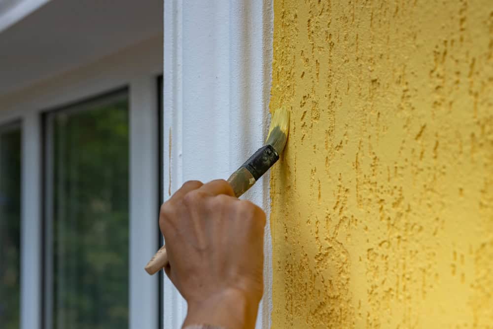Painting a sunny yellow wall, adding a touch of brightness to the day.