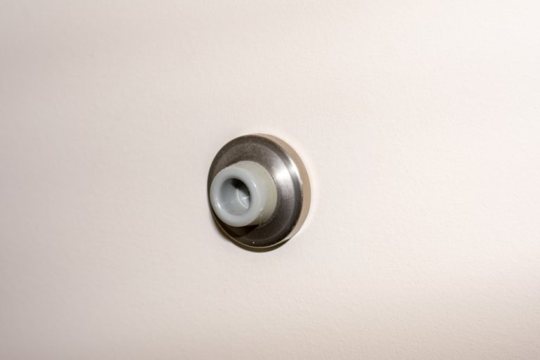 Wall-mounted rubber door stopper protecting surfaces from damage.