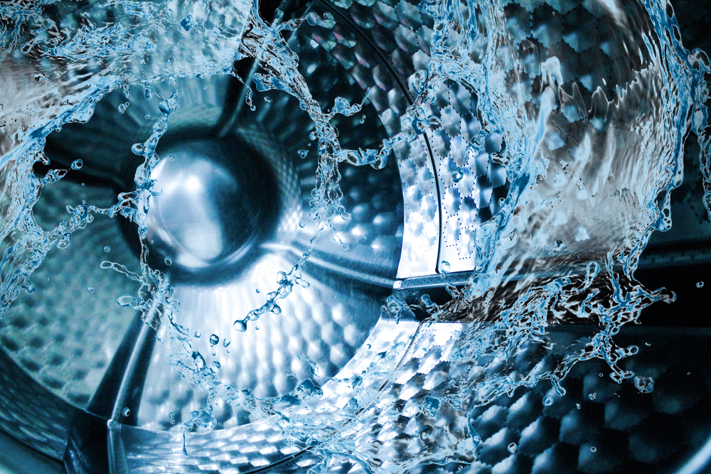 Inside a Washing Machine: Dynamic water splashes and ripples captured in cool blue tones against the textured stainless steel drum during a wash cycle.