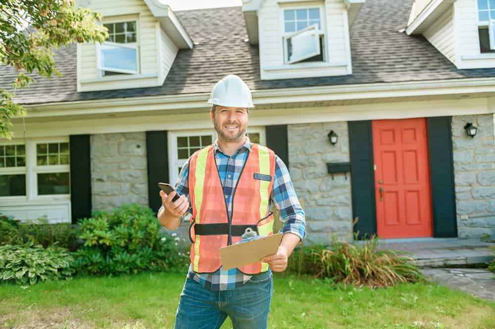 Smiling home inspector stands ready with clipboard and phone.