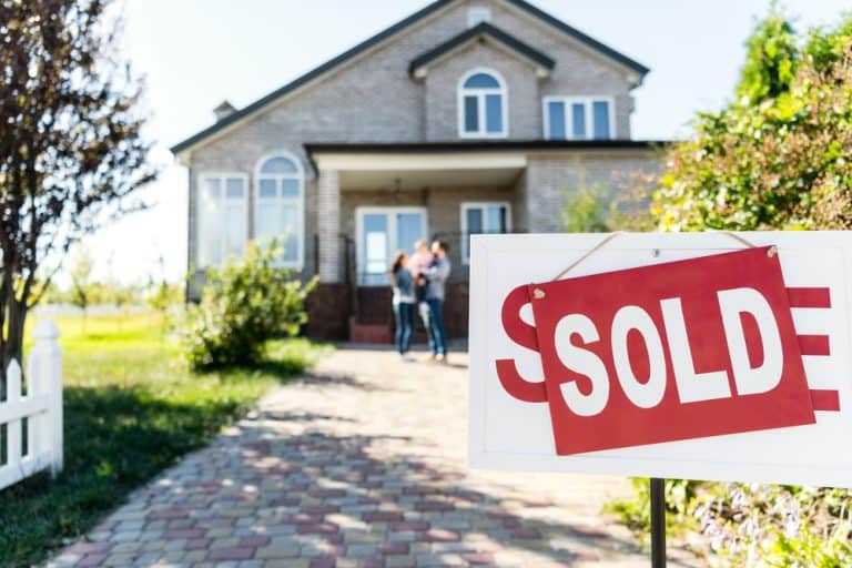 A family celebrates in front of their newly sold home.