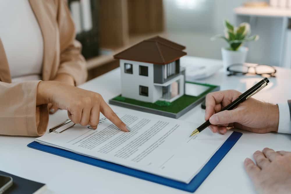 Signing the deal for a new home, with the model house and contract on the table.