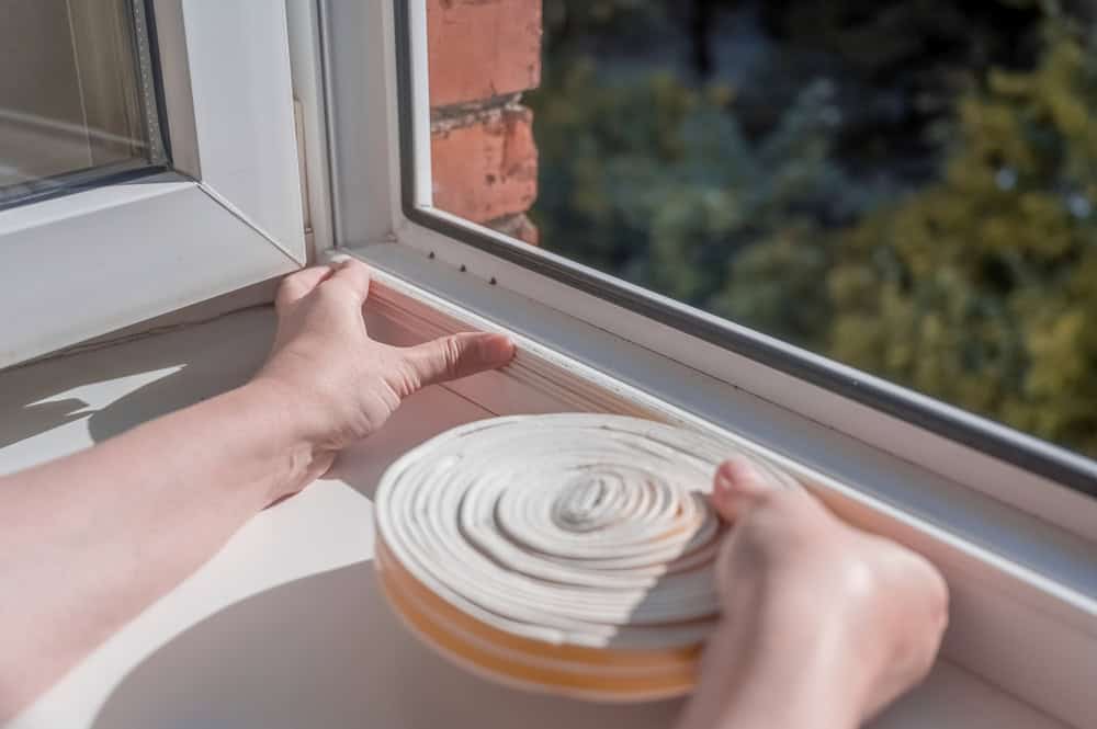 Sealing the window with weatherproof tape to keep the drafts out.