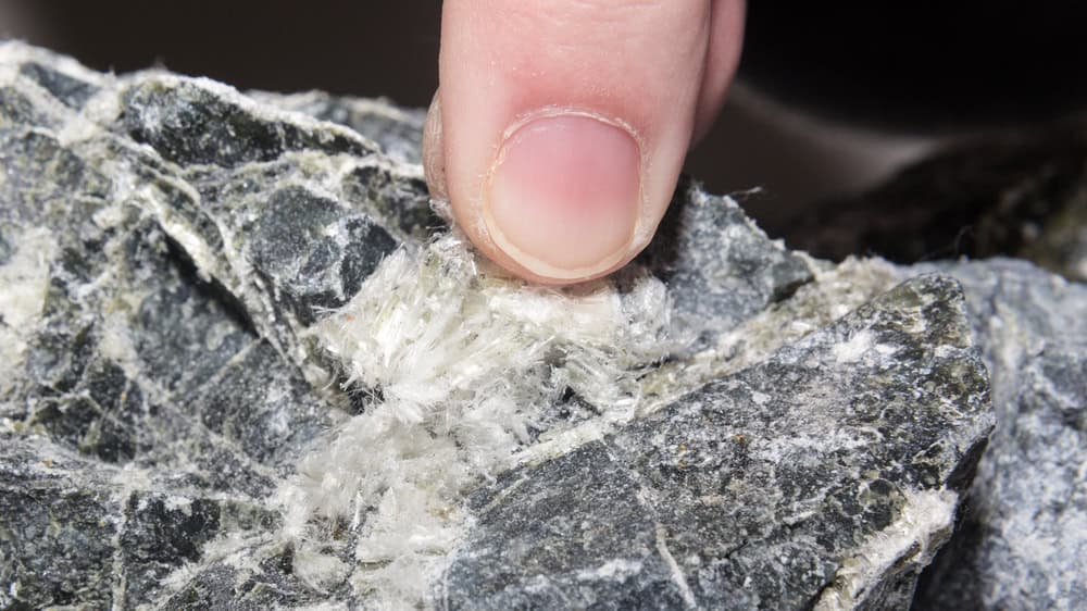 A close-up of raw asbestos fibers in a rock.
