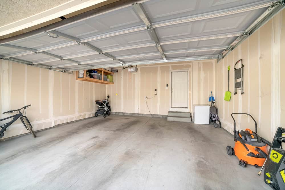 A clean, organized garage with a bike, strollers, and a lawnmower
