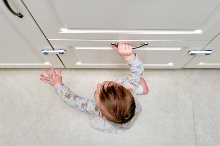 Curious little explorer reaches for kitchen drawers protected by child safety locks.