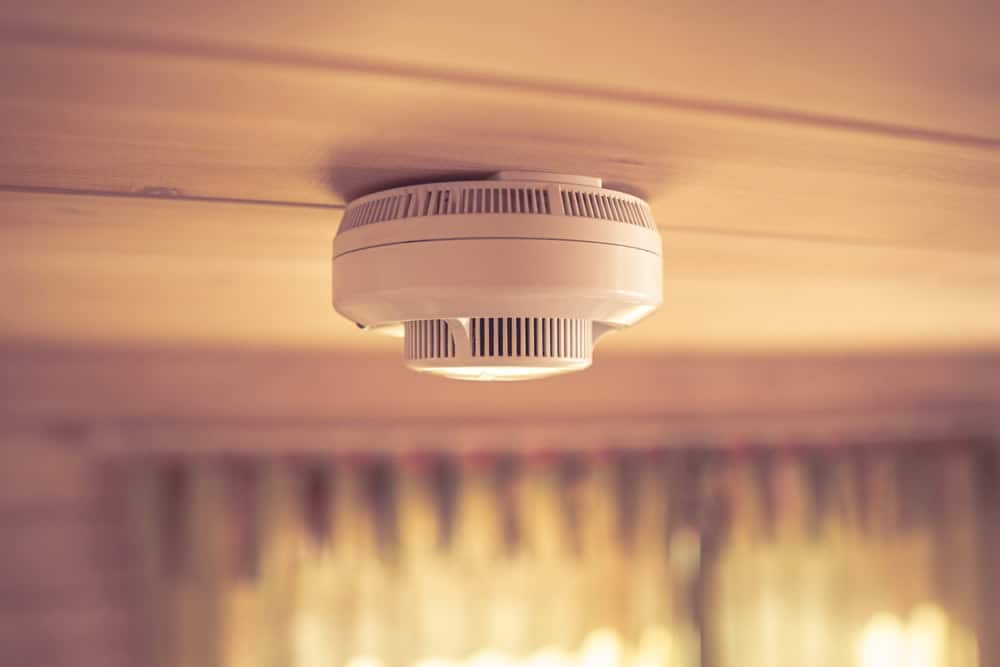 A smoke detector watches over a warmly lit room, ensuring safety from above.