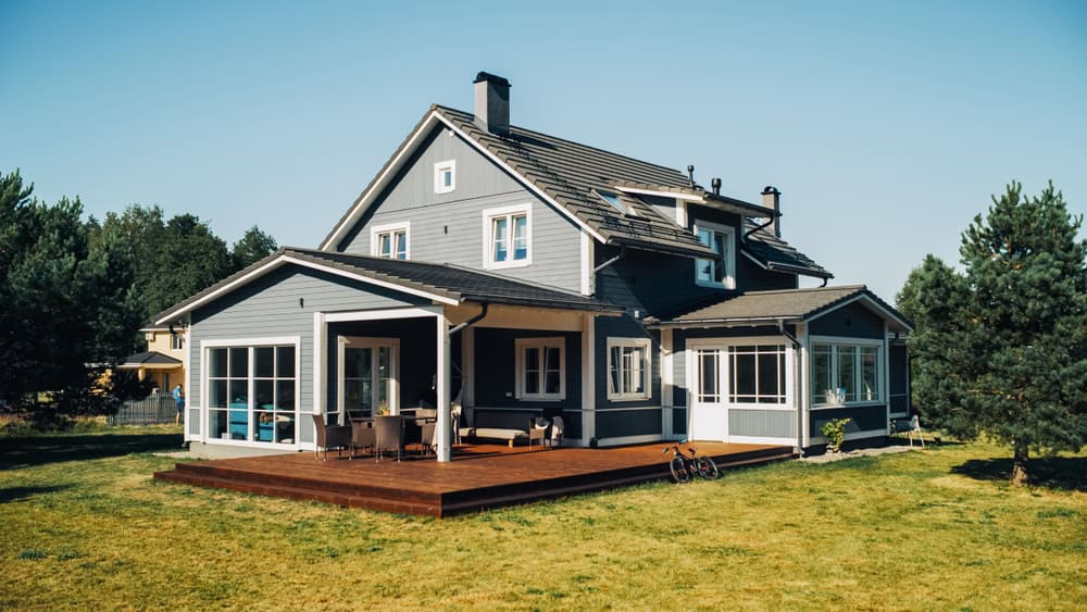 A cozy modern home with a spacious deck, surrounded by lush greenery and a serene backyard.
