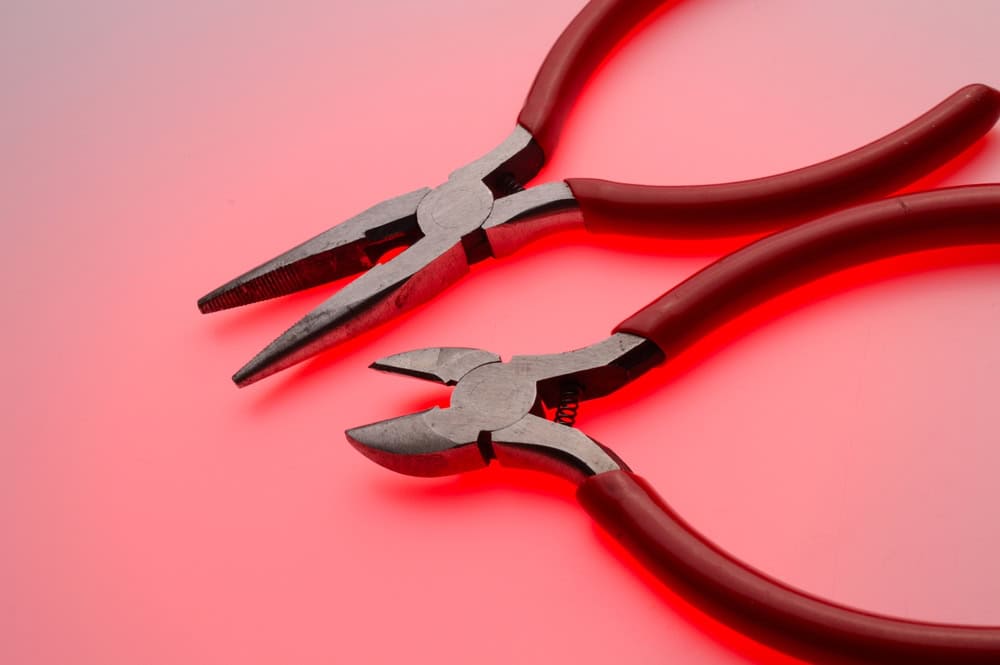 Precision tools in harmony—needle-nose and diagonal pliers on a glowing red backdrop.