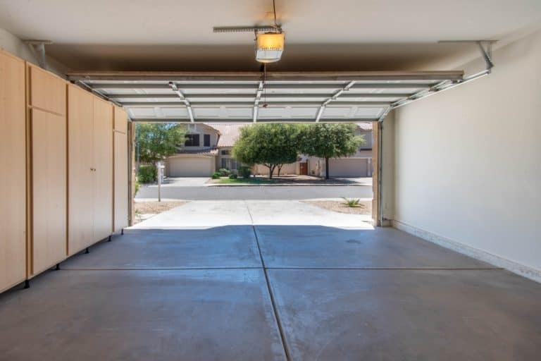 A spacious, well-lit garage with the door open, revealing a quiet suburban street.