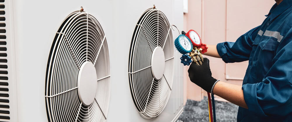 An HVAC technician servicing an air conditioning unit with precision tools.