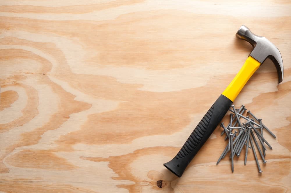 A sturdy hammer and nails ready for action on a wooden surface.