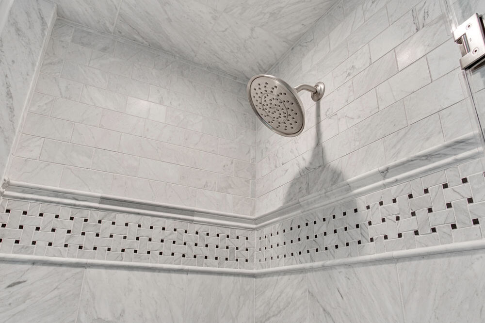 Elegant marble-tiled shower with a modern rainfall showerhead.