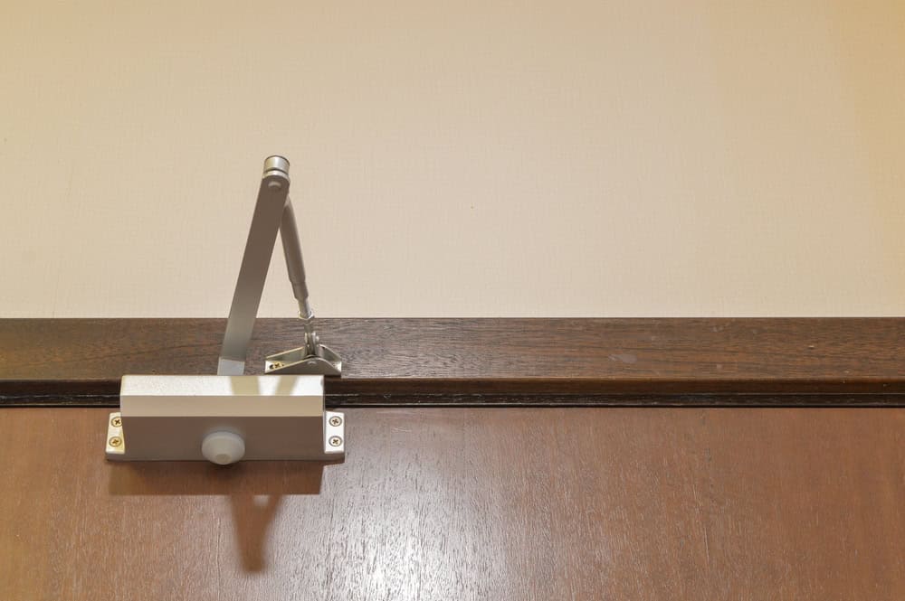 A sleek door closer mechanism mounted on a wooden door.