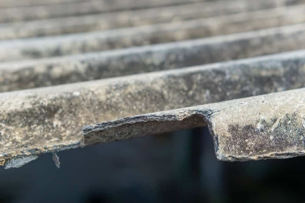 Close-up of weathered and brittle asbestos roofing sheets.