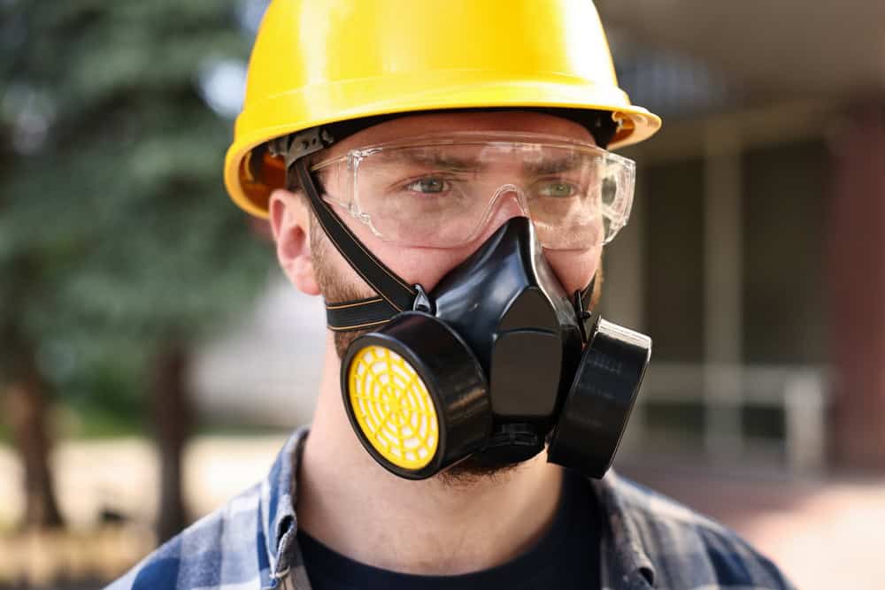 A worker in a yellow hard hat and protective mask ensures safety on the job site.