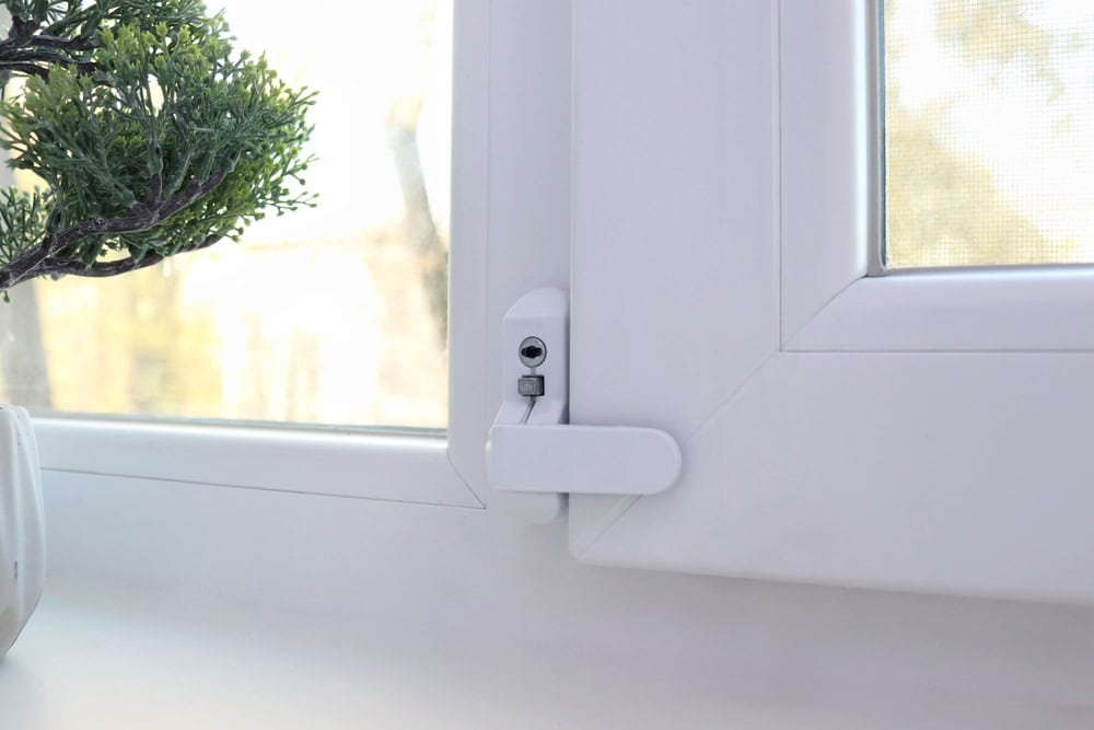 A close-up of a white plastic window lock latch.