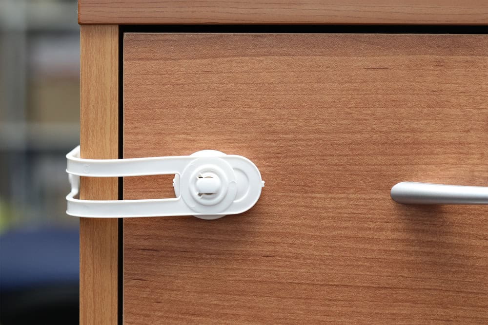 Child safety lock securing a wooden cabinet drawer, preventing access and ensuring safety in the home.
