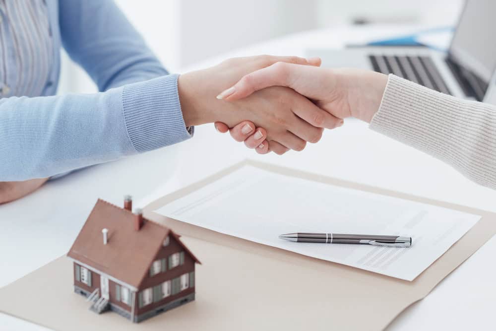 Sealing the deal on a new home with a firm handshake, pen ready to sign the paperwork.