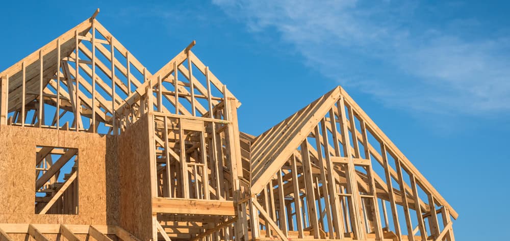 New homes take shape under clear blue skies as wooden frames.