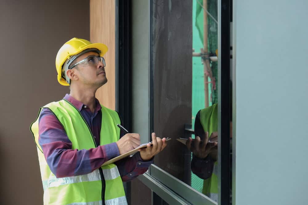 Construction inspector meticulously reviewing window installation.