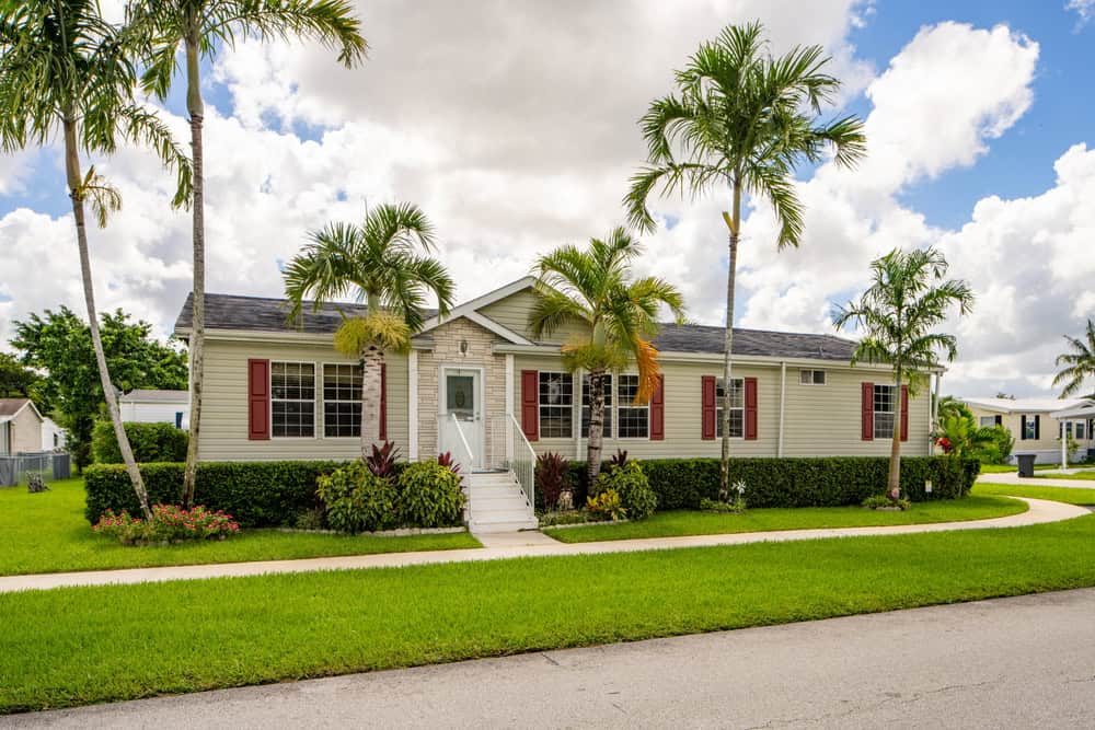 A charming mobile home surrounded by lush greenery and palm trees.