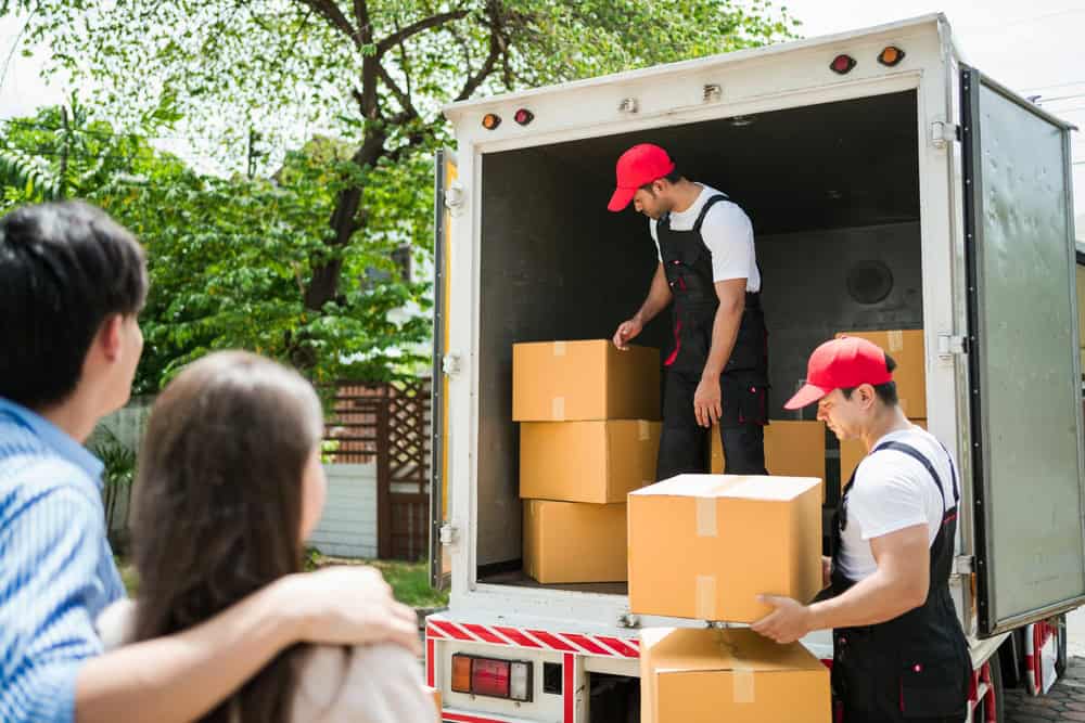 Movers loading boxes into a truck as a family watches.