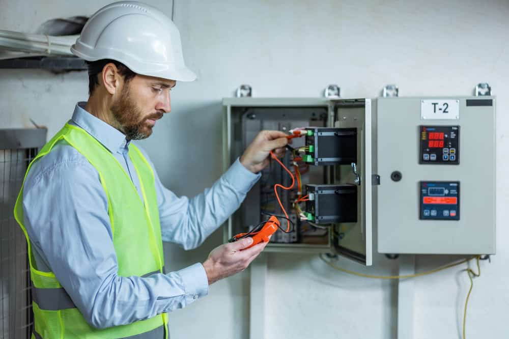 Engineer testing electrical panel T-2 with a multimeter.