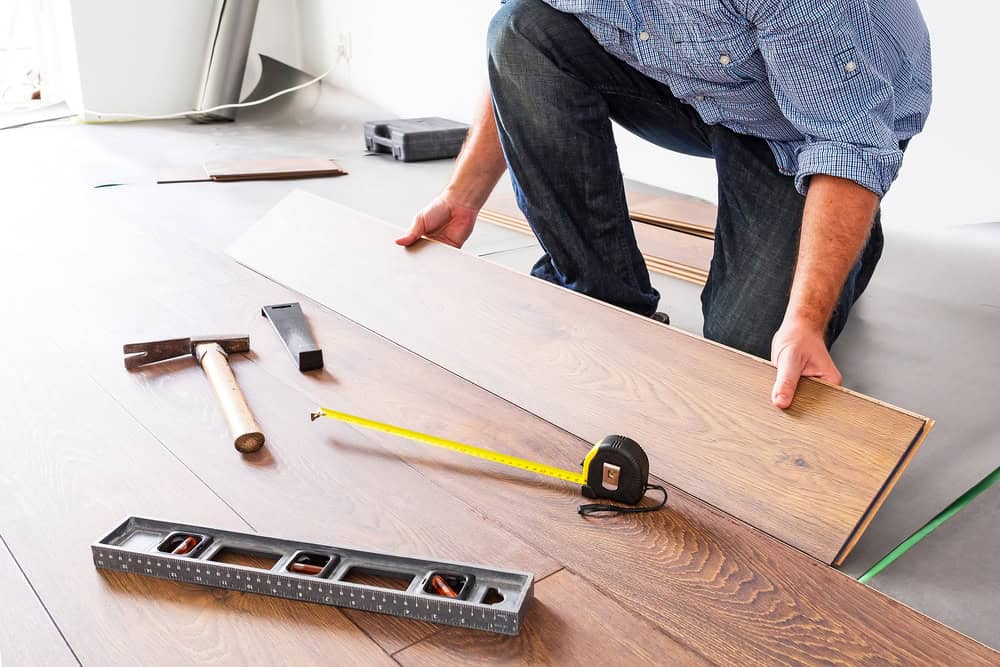 A handyman installs new hardwood flooring with precision tools.