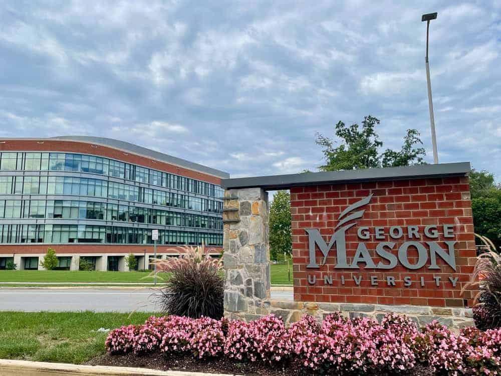 Modern campus meets tradition: George Mason University’s sleek architecture and vibrant landscaping welcome students under a dramatic sky.