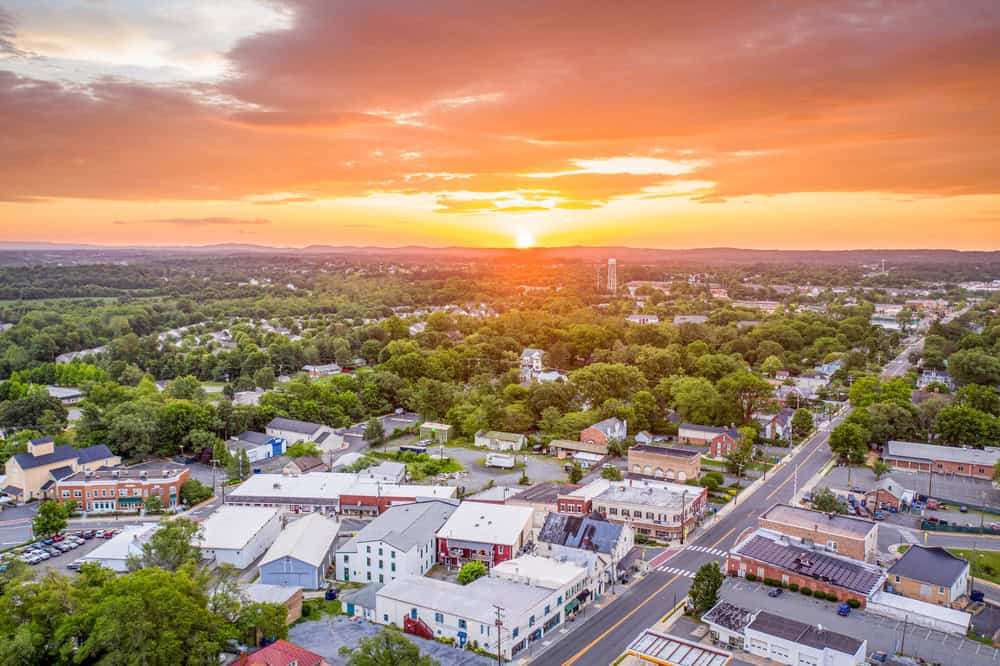 Golden hour bathes the charming town of Purcellville, Virginia in warm light, as the sun sets over its historic downtown and lush, tree-filled landscape.