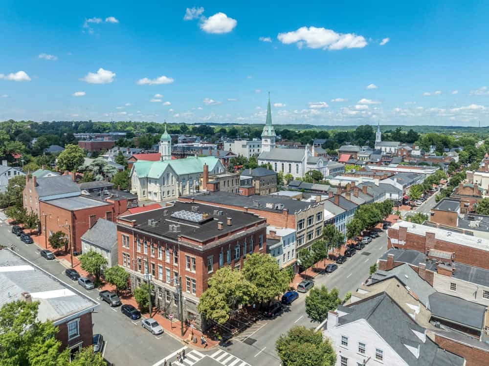 Aerial view of a charming small town with historic buildings, tree-lined streets, and a prominent church steeple.
