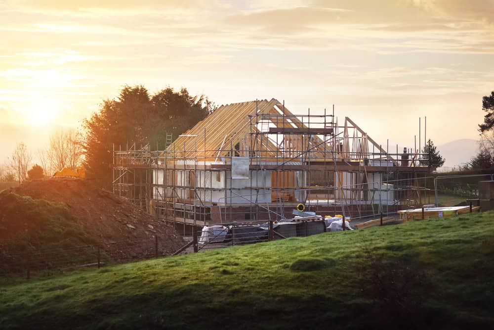A new home under construction in the serene countryside, bathed in the golden light of a setting sun.