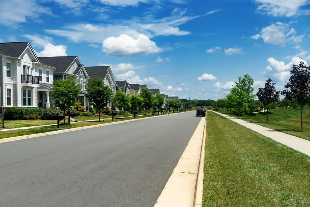 A serene suburban neighborhood with charming homes, tree-lined streets, and a clear blue sky.