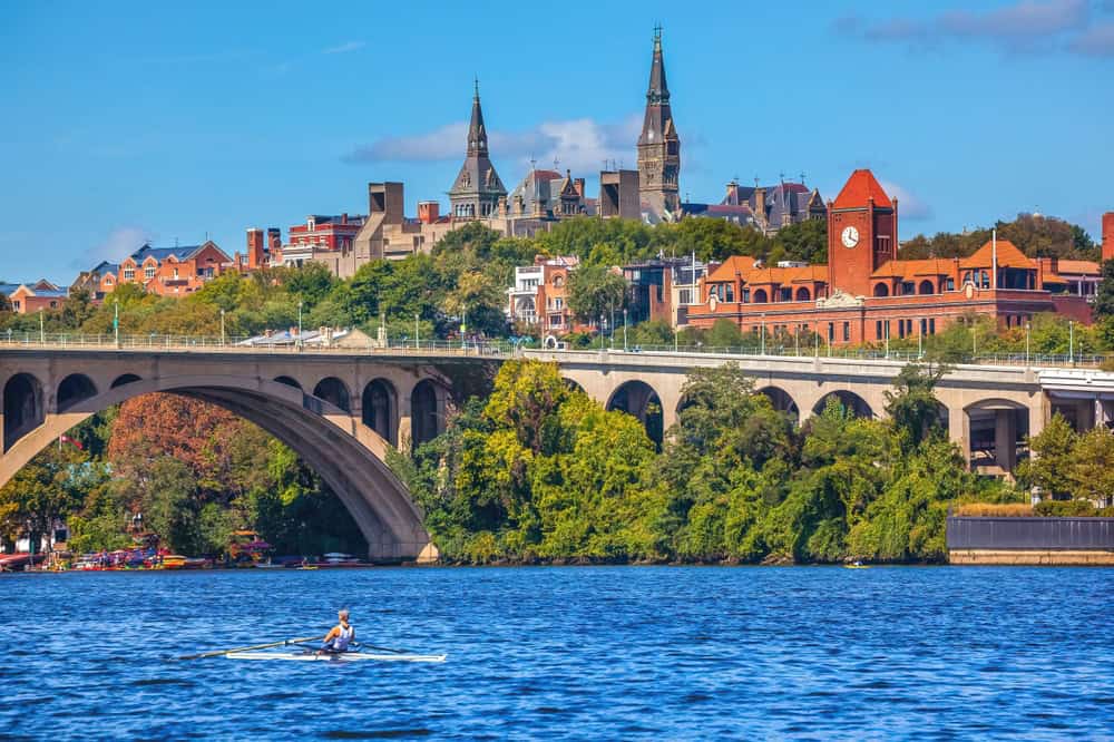 Rowing under the Key Bridge with Georgetown University's iconic Healy Hall in the background.